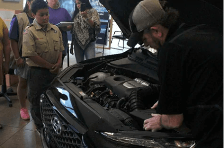 boy scout looking at car engine