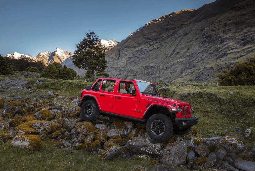 red jeep rubicon on rocks in the mountains