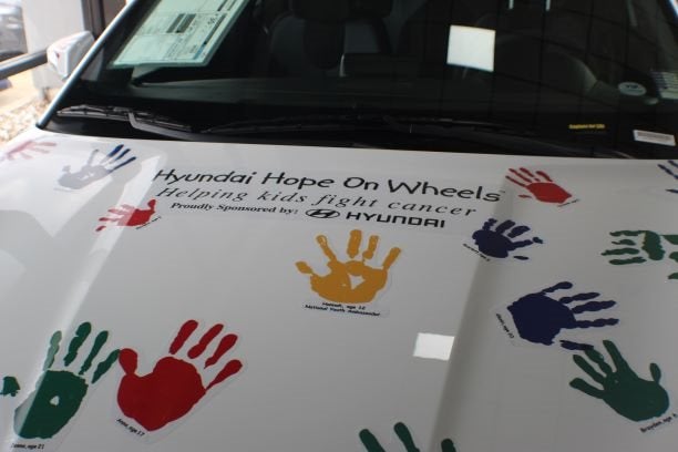 white hyundai covered in colorful hand prints